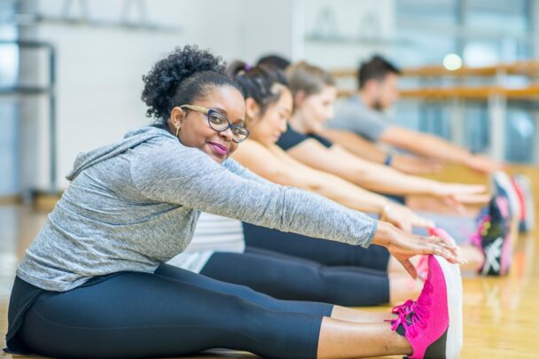 Groepje mensen doet zittend een stretchoefening.