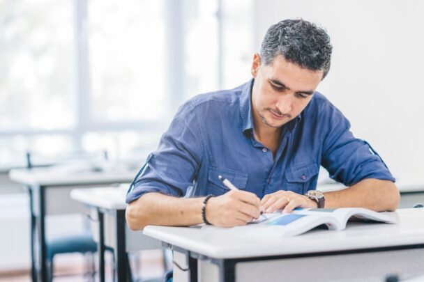 Man van middelbare leeftijd is aan het schrijven en lezen, of studeren.