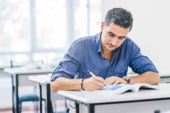 Man van middelbare leeftijd is aan het schrijven en lezen, of studeren.