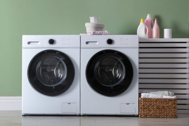 Wasmachine en droger tegen een lichtgroene muur.