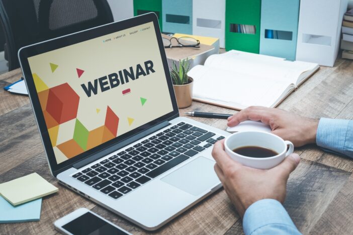 Iemand zit klaar achter een laptop voor een webinar.