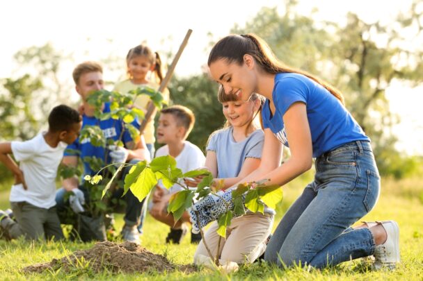 Twee volwassenen en groepje kids plant samen een boopje.