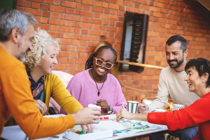 Vijf mensen spelen een bordspelletje.