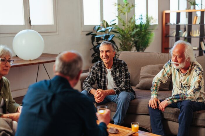 Vier mensen voeren een gesprek in een gezellige setting.