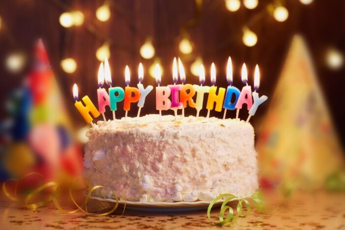 Een feestelijke taart met brandende kaarsjes.