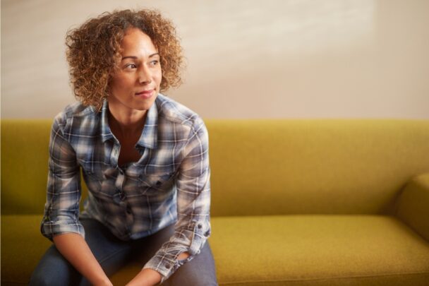 Vrouw zit op een okergele bank.