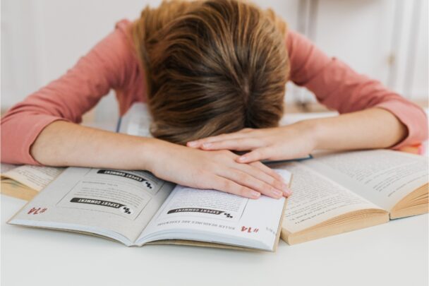 Meisje heeft examenstress en ligt op haar boek.