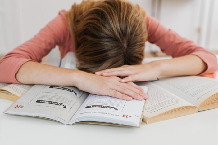 Meisje heeft examenstress en ligt op haar boek.