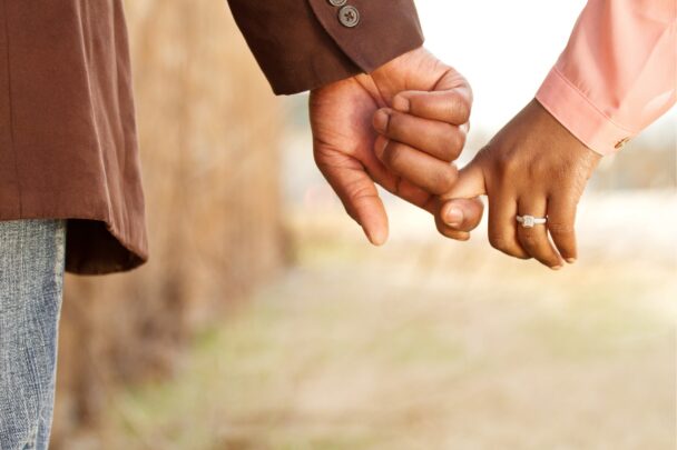 Man en vrouw houden heel losjes elkaars hand vast.