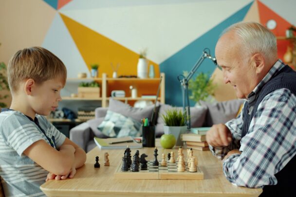 Jongen en oudere man spelen schaak.