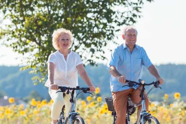 Ouder stel fietst samen langs zonnebloemenveld.