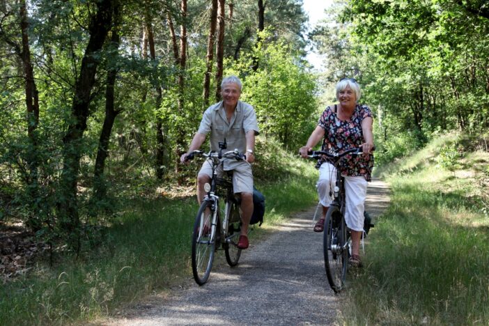 Ouder stel fietst samen door het bos.
