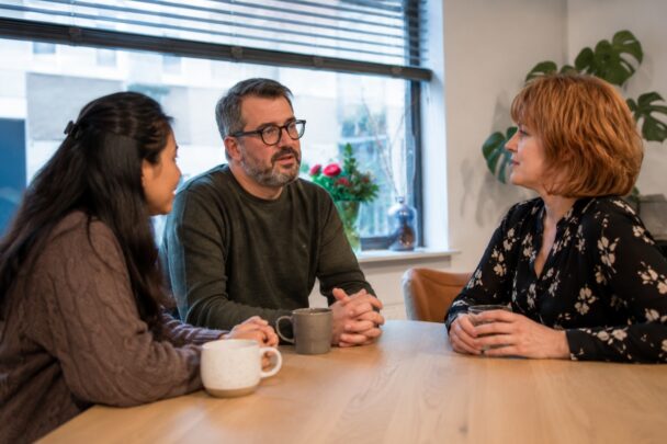 Gesprek aan tafel tussen twee vrouwen en een man,
