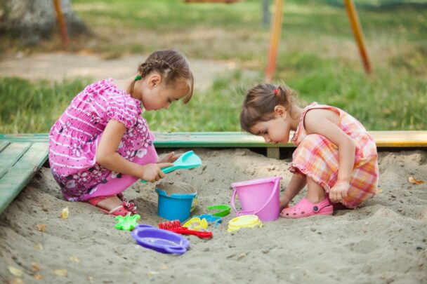Twee meisjes spelen in een zandbak.