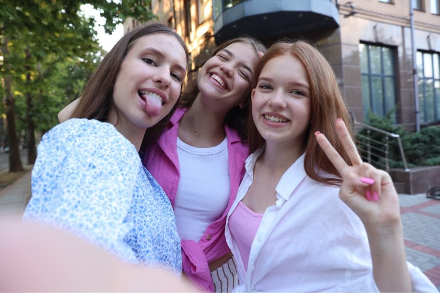Drie jonge meiden maken een selfie met een smartphone.