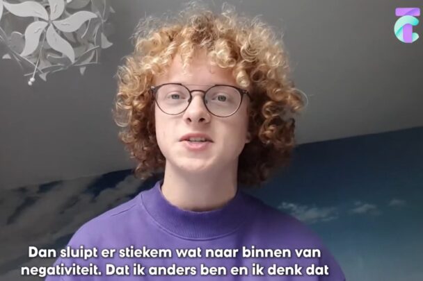 Jongen met roodblonde krullen en bril is aan het vertellen.
