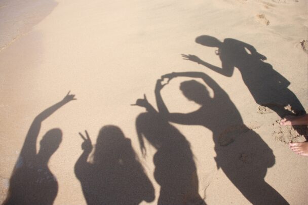De schaduw van 5 mensen op het strand.