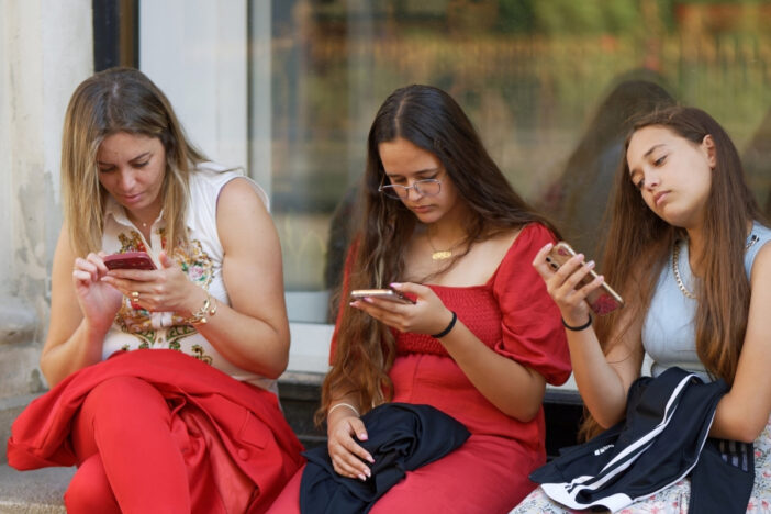 Drie meiden gebruiken hun smartphones.
