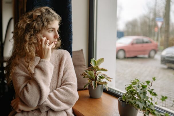 Jonge vrouw kijkt naar buiten door een raam.