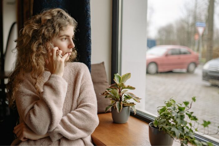 Jonge vrouw kijkt naar buiten door een raam.
