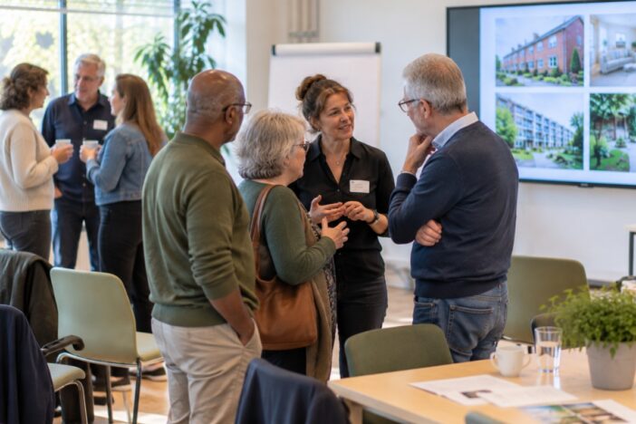 Groepje mensen praat na met elkaar na een bijeenkomst met presentatie.